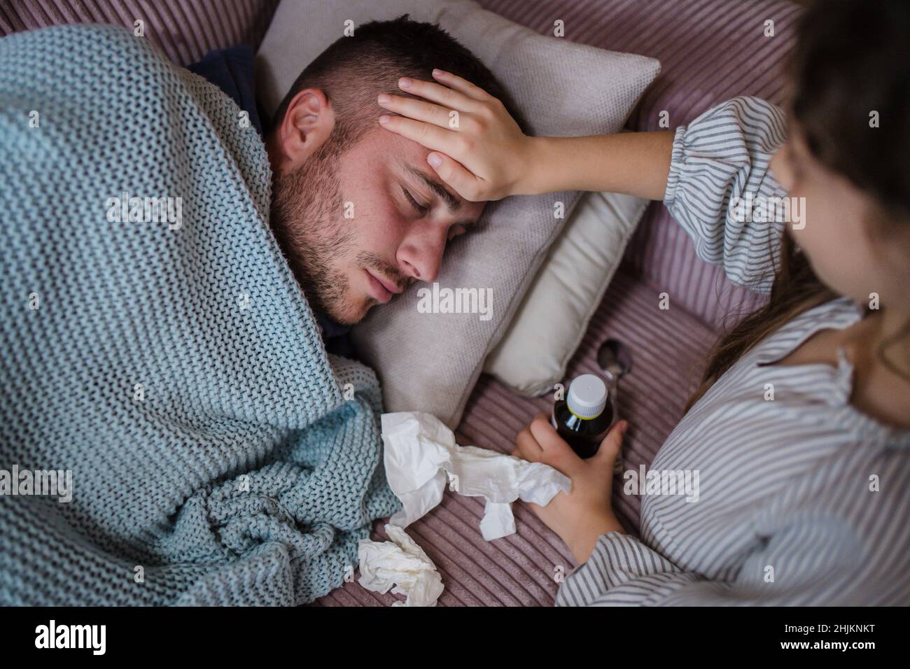 High angle view of little daughter taking care of her sick father at home. Stock Photo