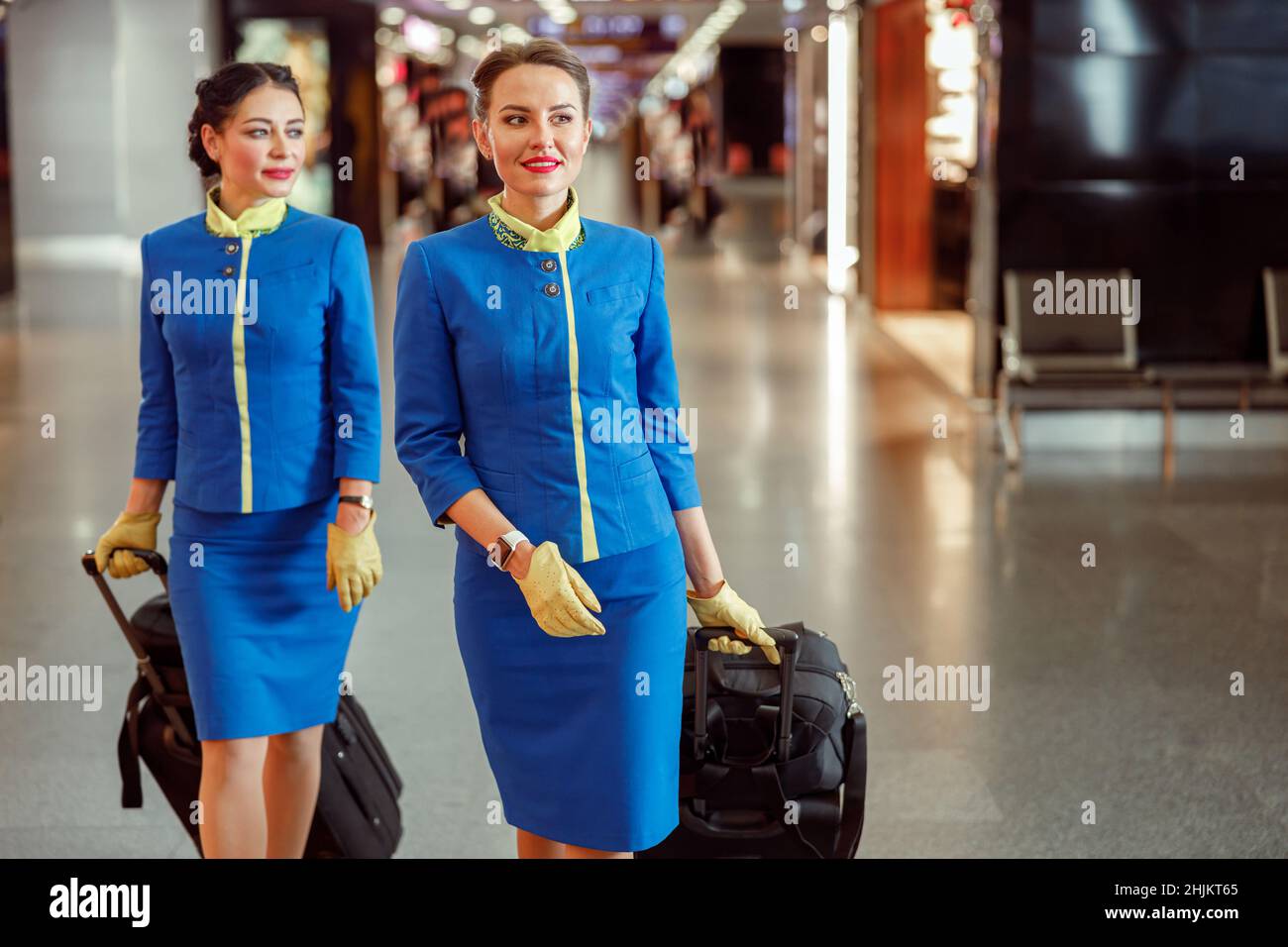 Female flight attendants carrying travel bags at airport Stock Photo
