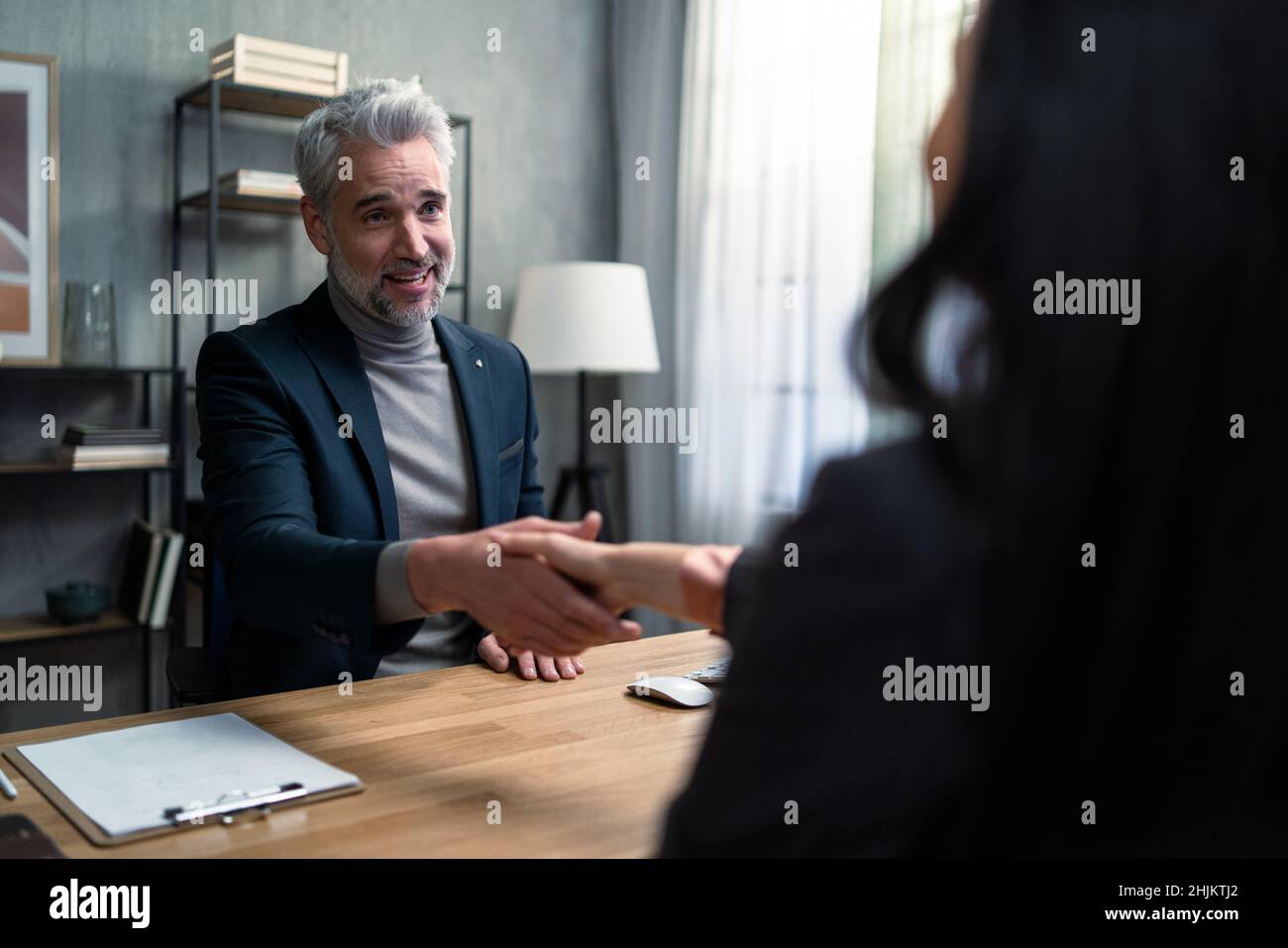 Mature financial advisor shaking hand with his client indoors in office. Stock Photo