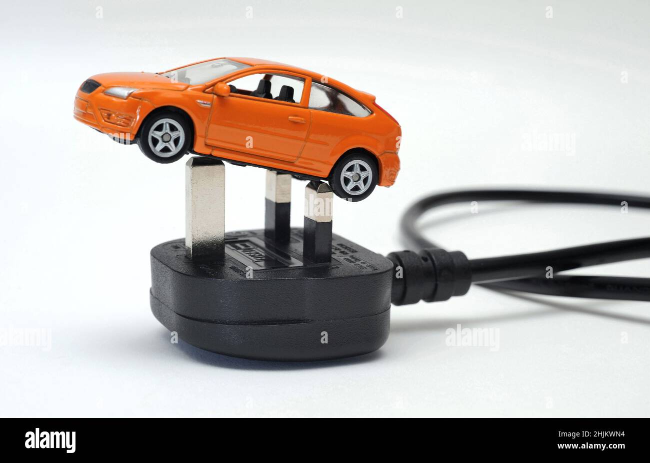 MODEL CAR ON ELECTRIC PLUG AND LEAD RE ELECTRIC CARS VEHICLE EV ZERO EMISSIONS GREEN MOTORING PETROL DIESEL FOSSIL FUEL ETC UK Stock Photo