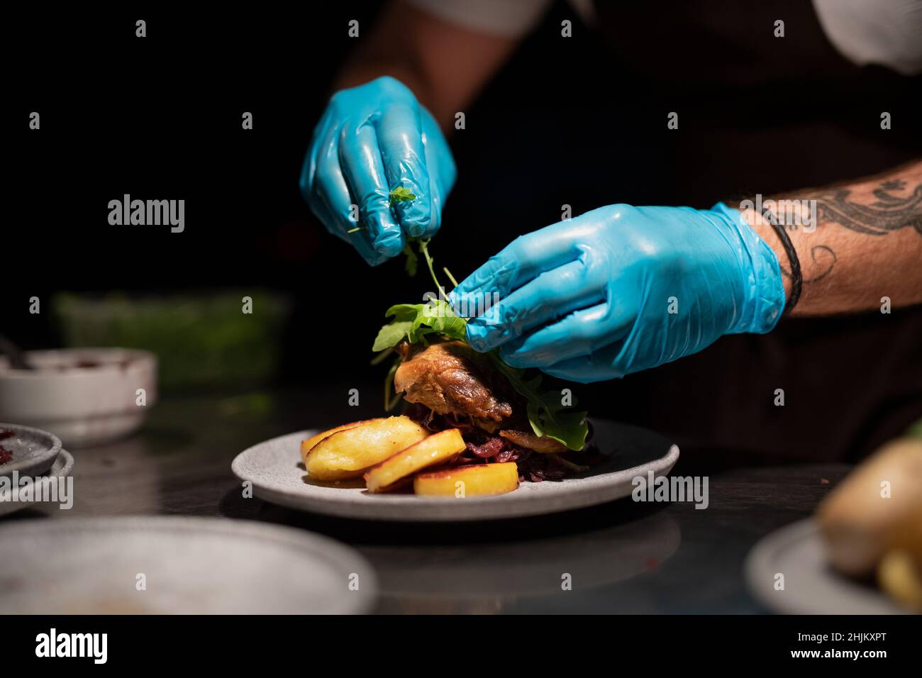 Chef's hands in gloves serving and decorating meal in restaurant ...