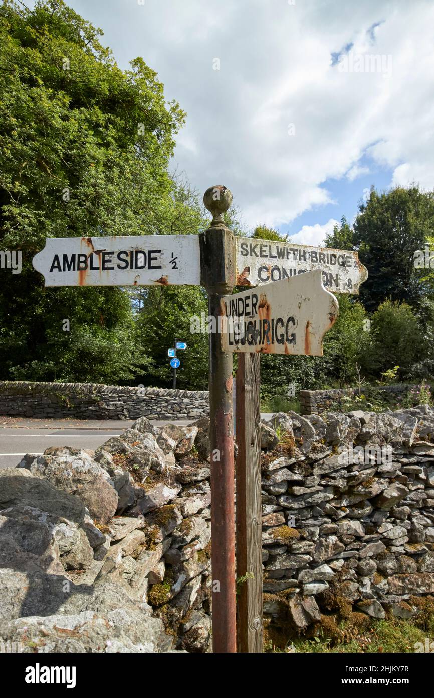 old white painted direction signs for ambleside under loughrigg skelwith bridge and coniston lake district, cumbria, england, uk Stock Photo