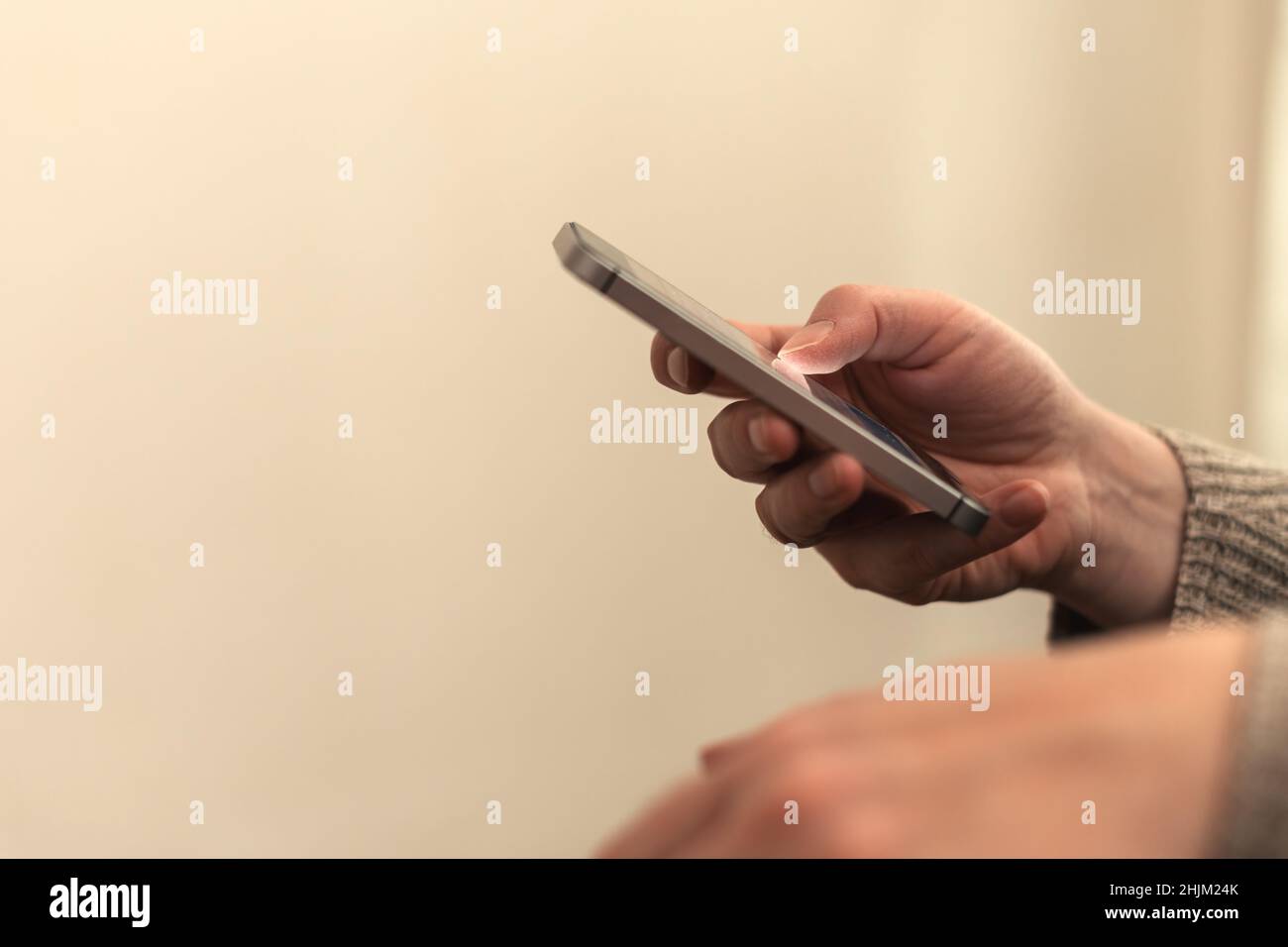 Closeup of female hands using smartphone for communication in living room, selective focus Stock Photo