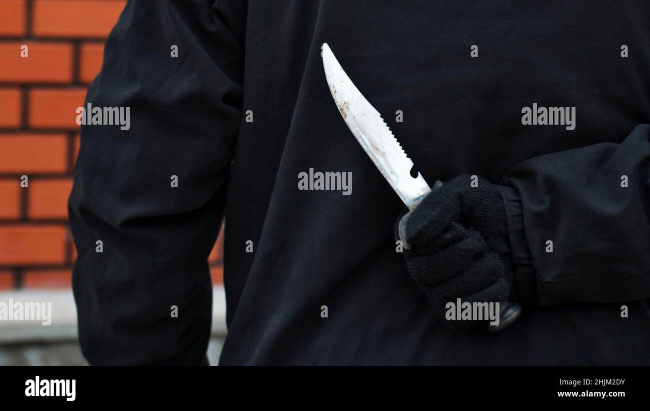 Man with the knife behind his back. Man holding sharp knife behind his