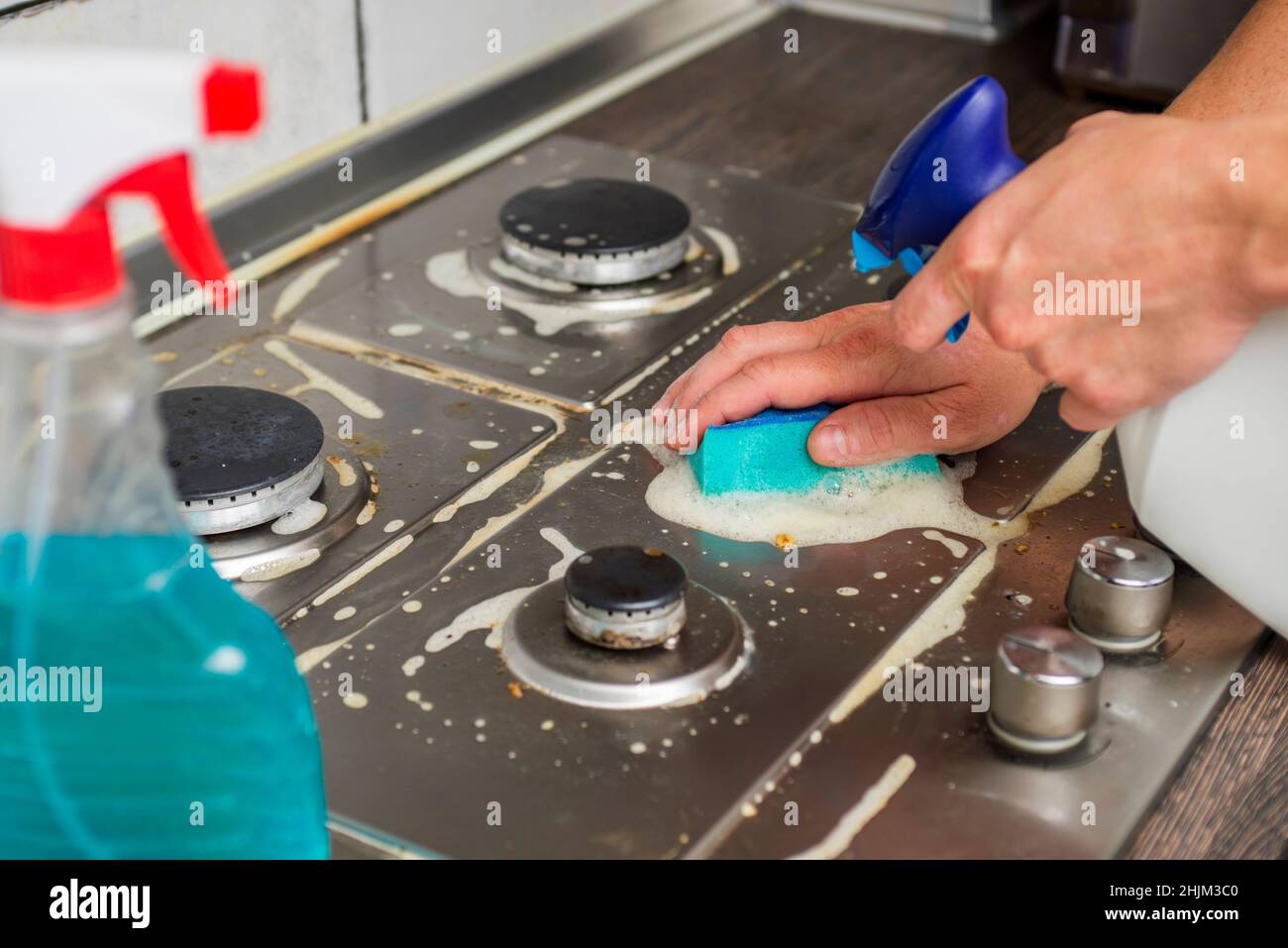 Man hand cleaning gas stove using sponge and detergents. Cleaning a gas