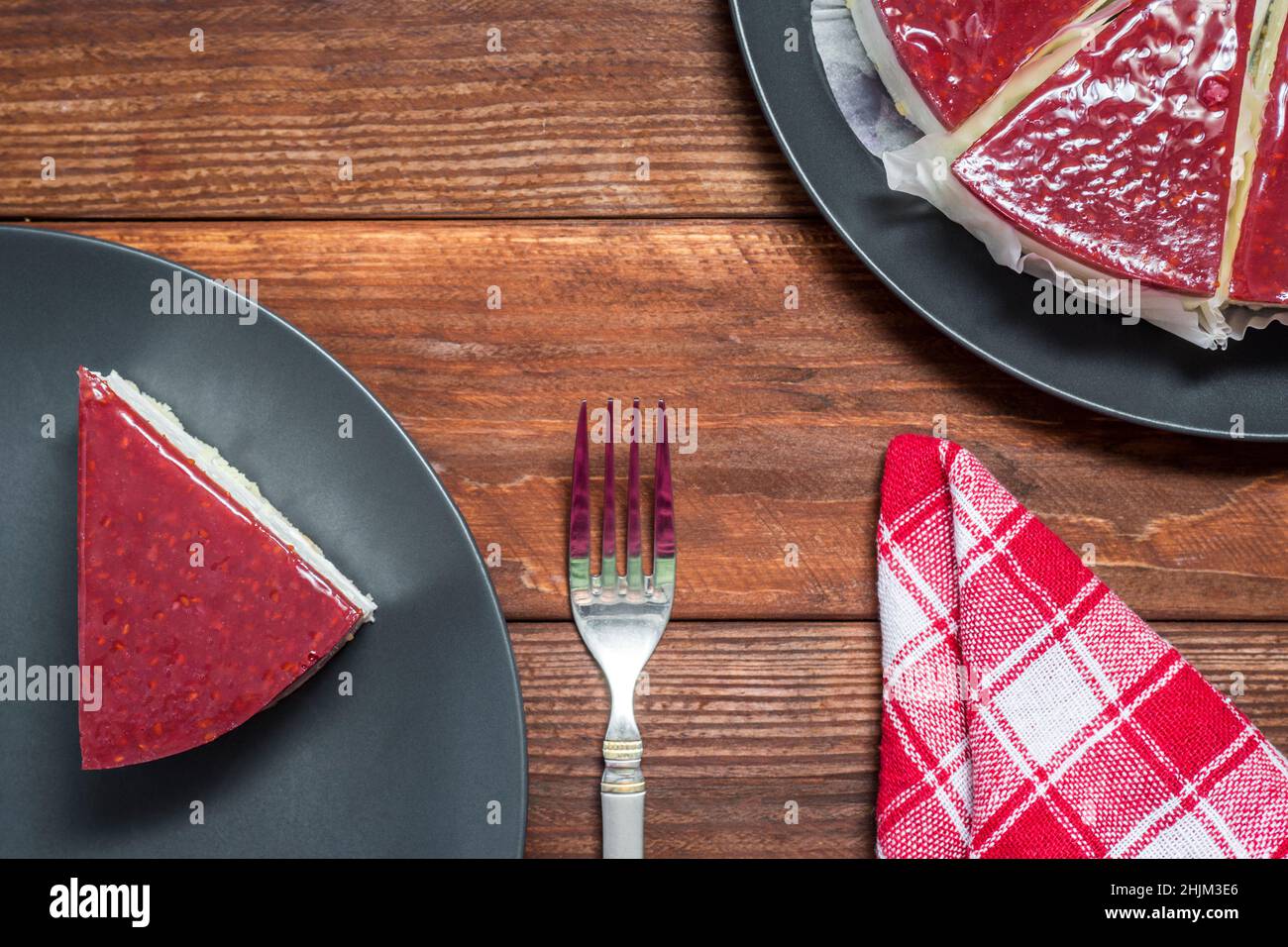 Classical cheesecake with raspberry jelly on rustic wood table background, top view. Stock Photo