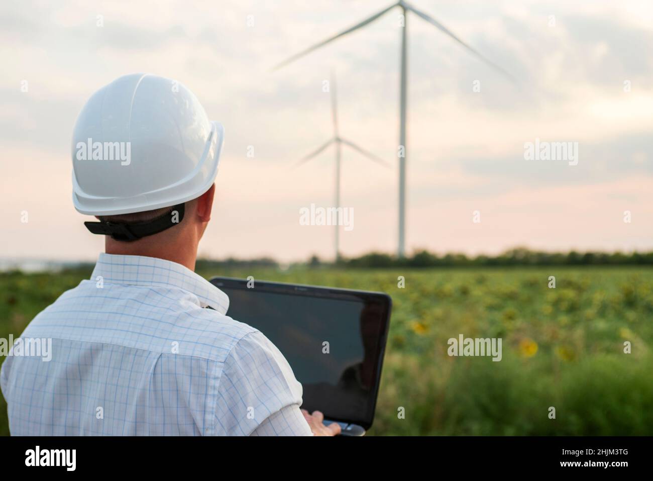 Engineer in a wind turbine. A man in a helmet with the tablet supervises the operation of the electric windmills. Ecology and renewable energy sources Stock Photo