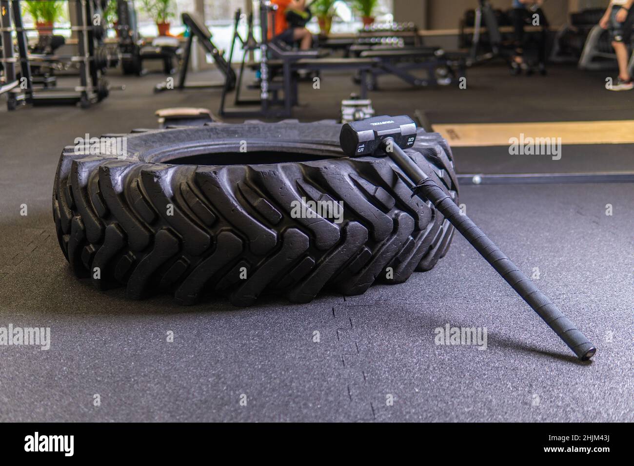 A tire on a black background with a sledgehammer lies for crosfit