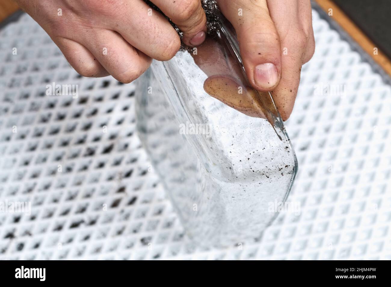 A man is cleaning a dirty baking dish with a thick layer of carbon with an  iron washcloth. Glassware for baking with soot, carbon deposits, old dried  fat Stock Photo - Alamy