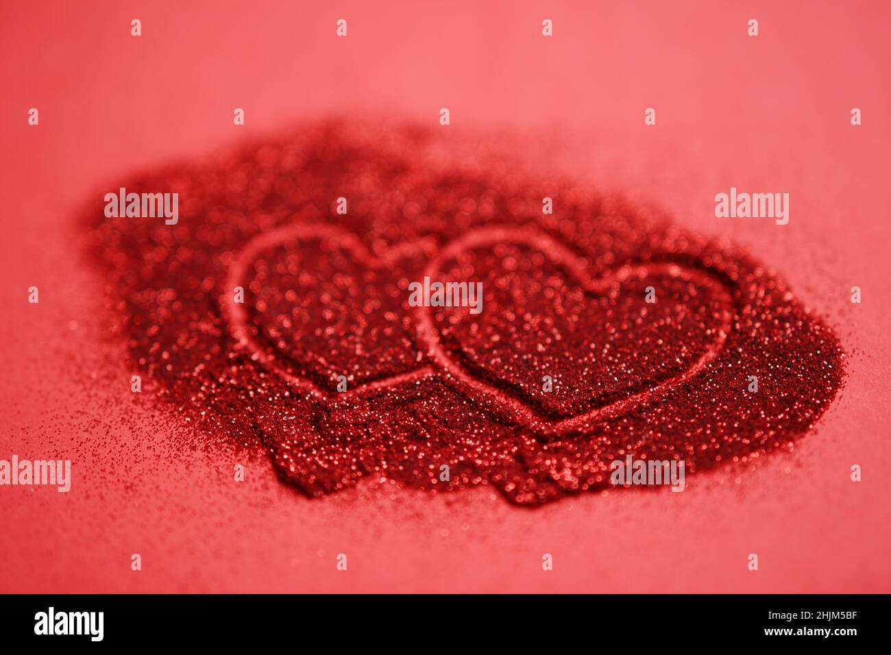 Red table with two hearts, finger painted on glitter. Stock Photo