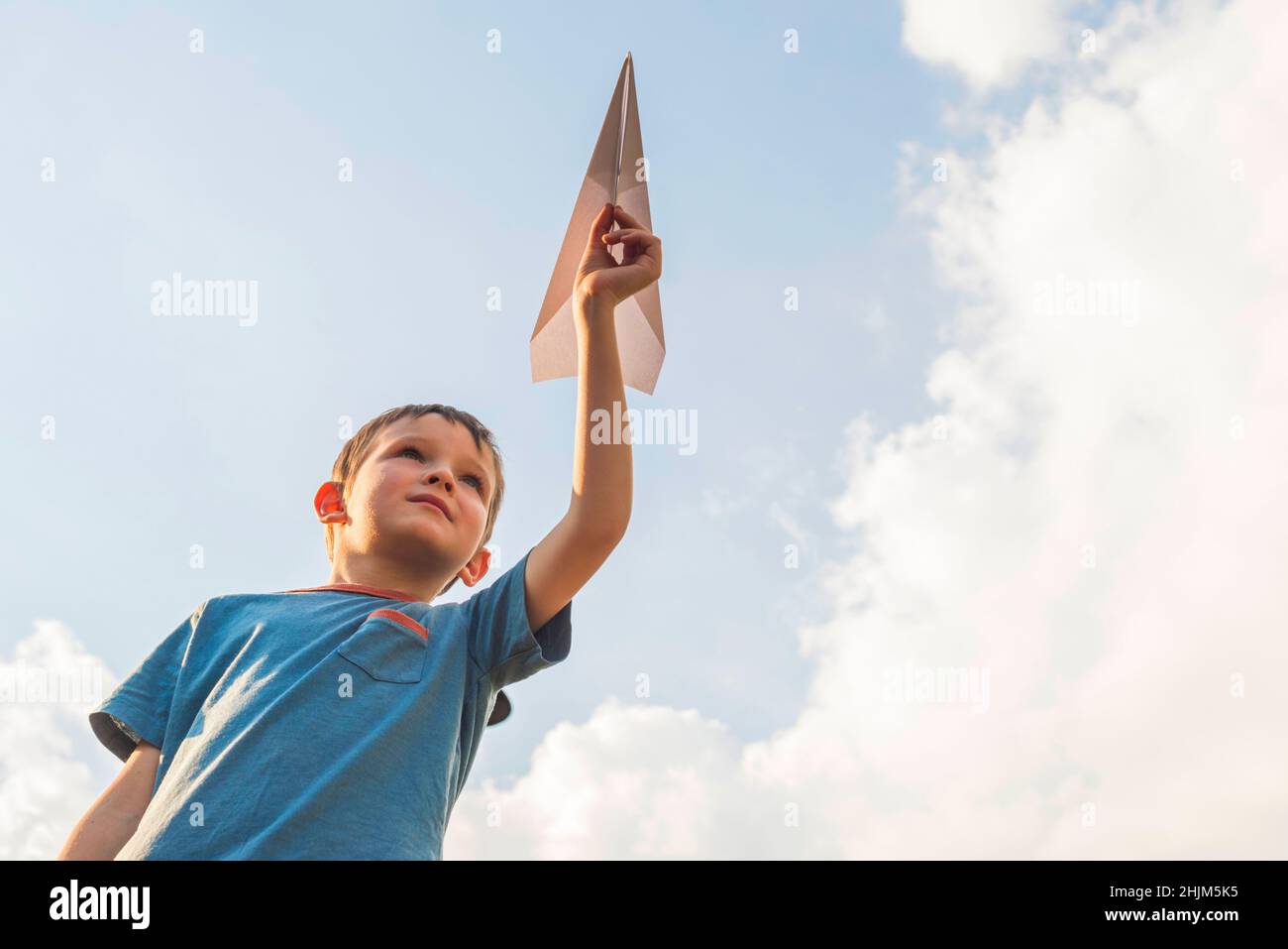 Happy child playing with paper airplane against the sky. A boy with ...