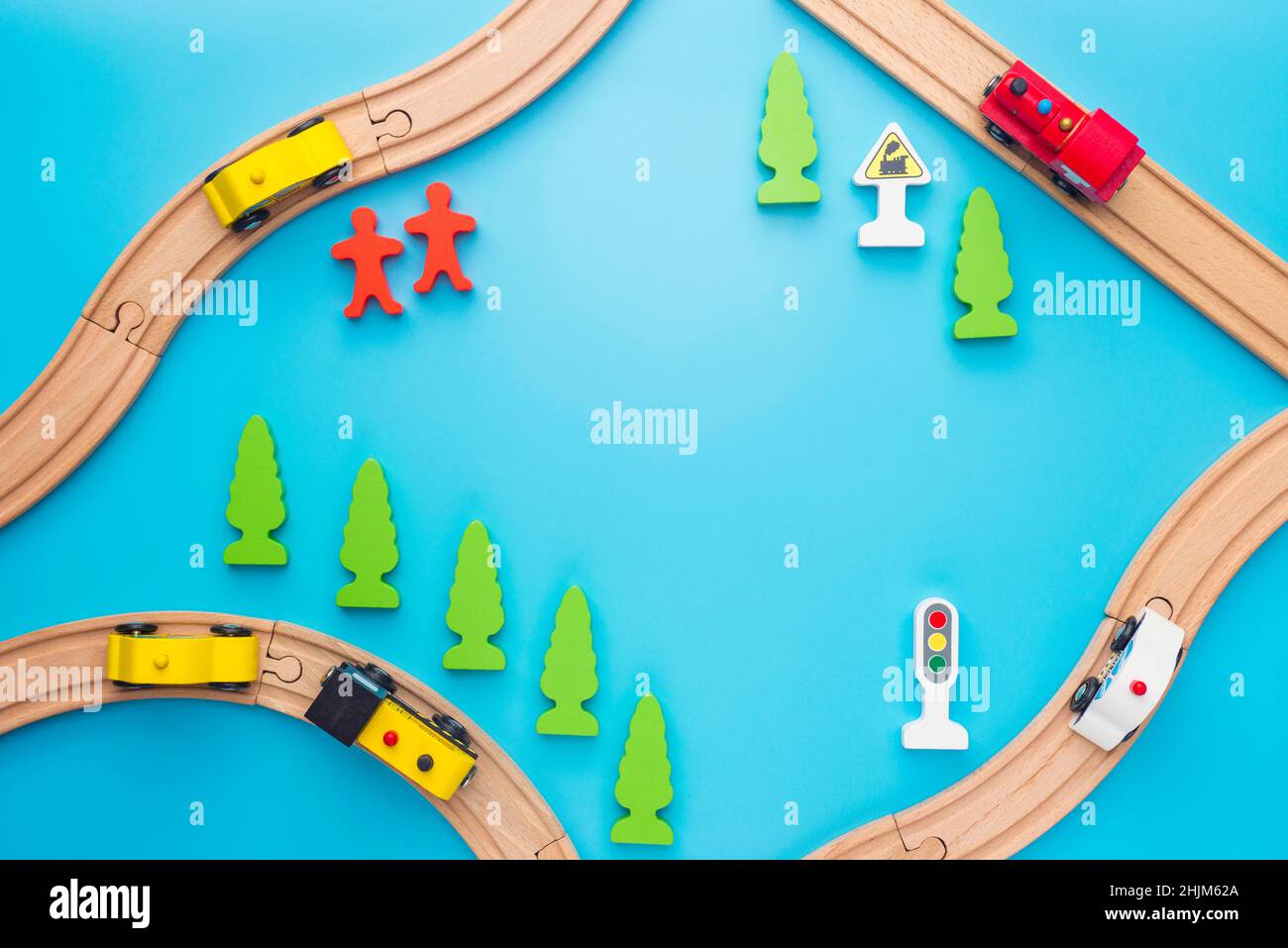 Baby kid toys background. Toy train and wooden rails on blue background. Top view. Children toys, a trains and cars traveling on wooden roads with tre Stock Photo