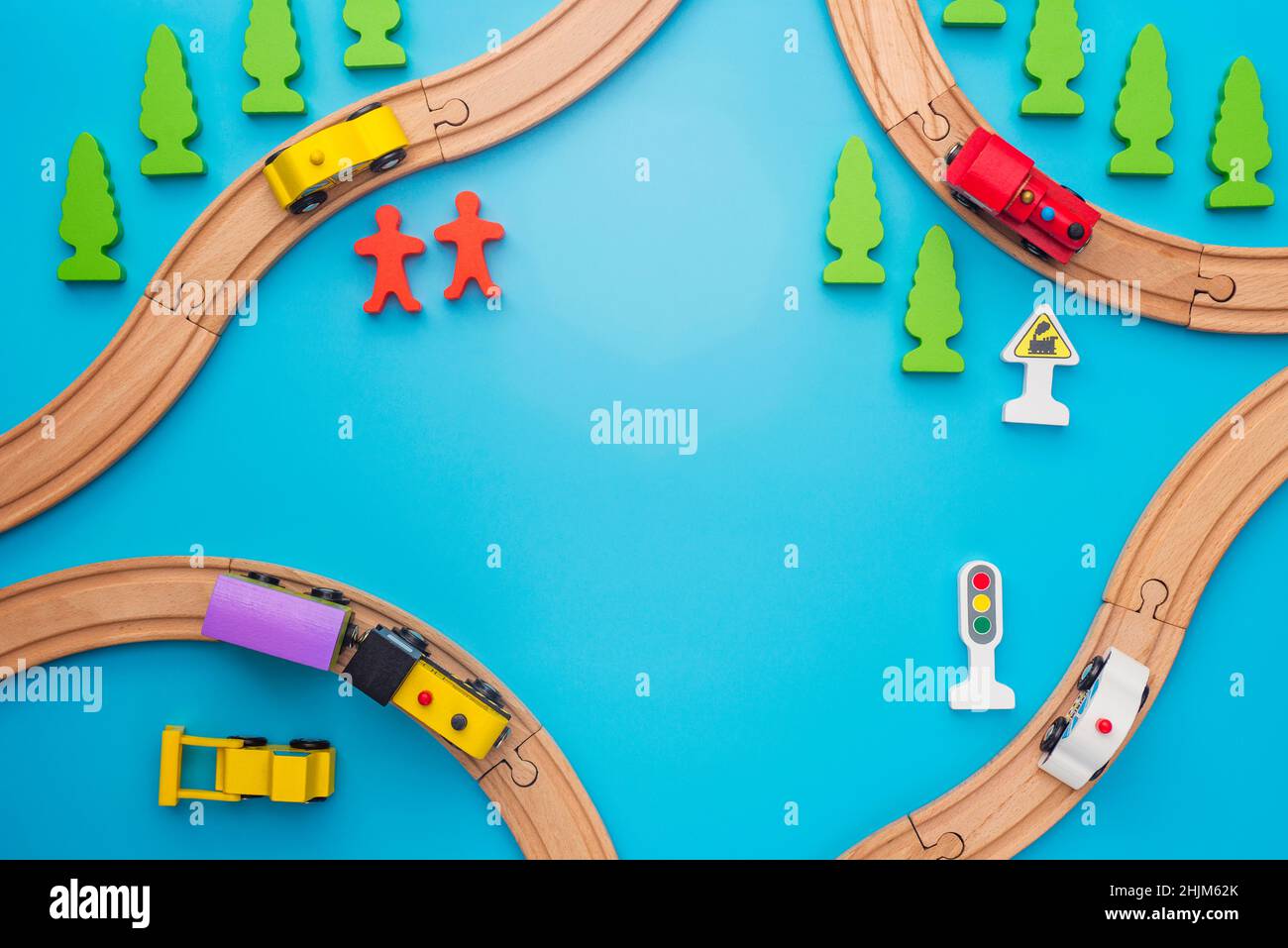 Baby kid toys background. Toy train and wooden rails on blue background. Top view. Children toys, a trains and cars traveling on wooden roads with tre Stock Photo