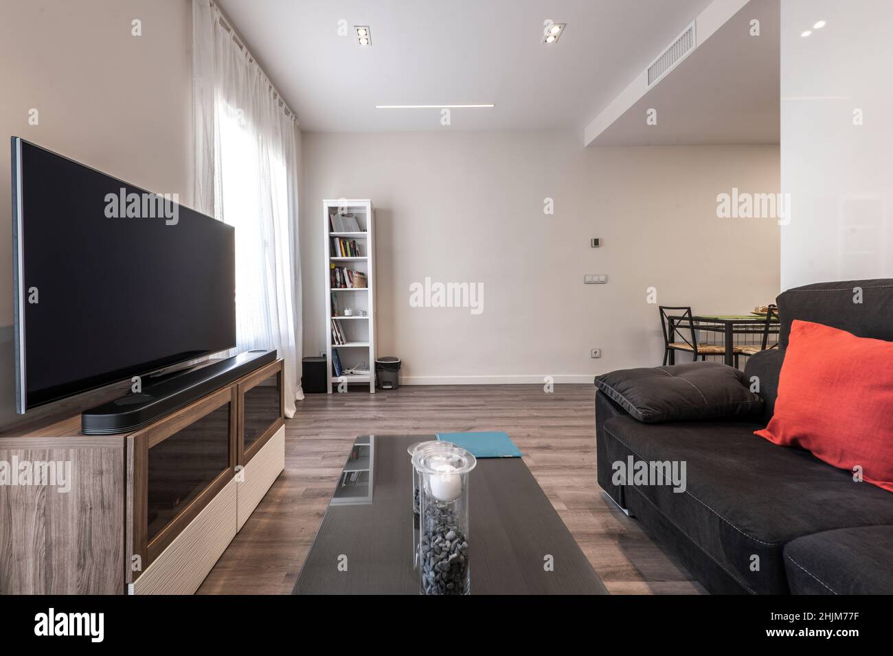 Living room with black velvet sofa, flat TV on a in front and
