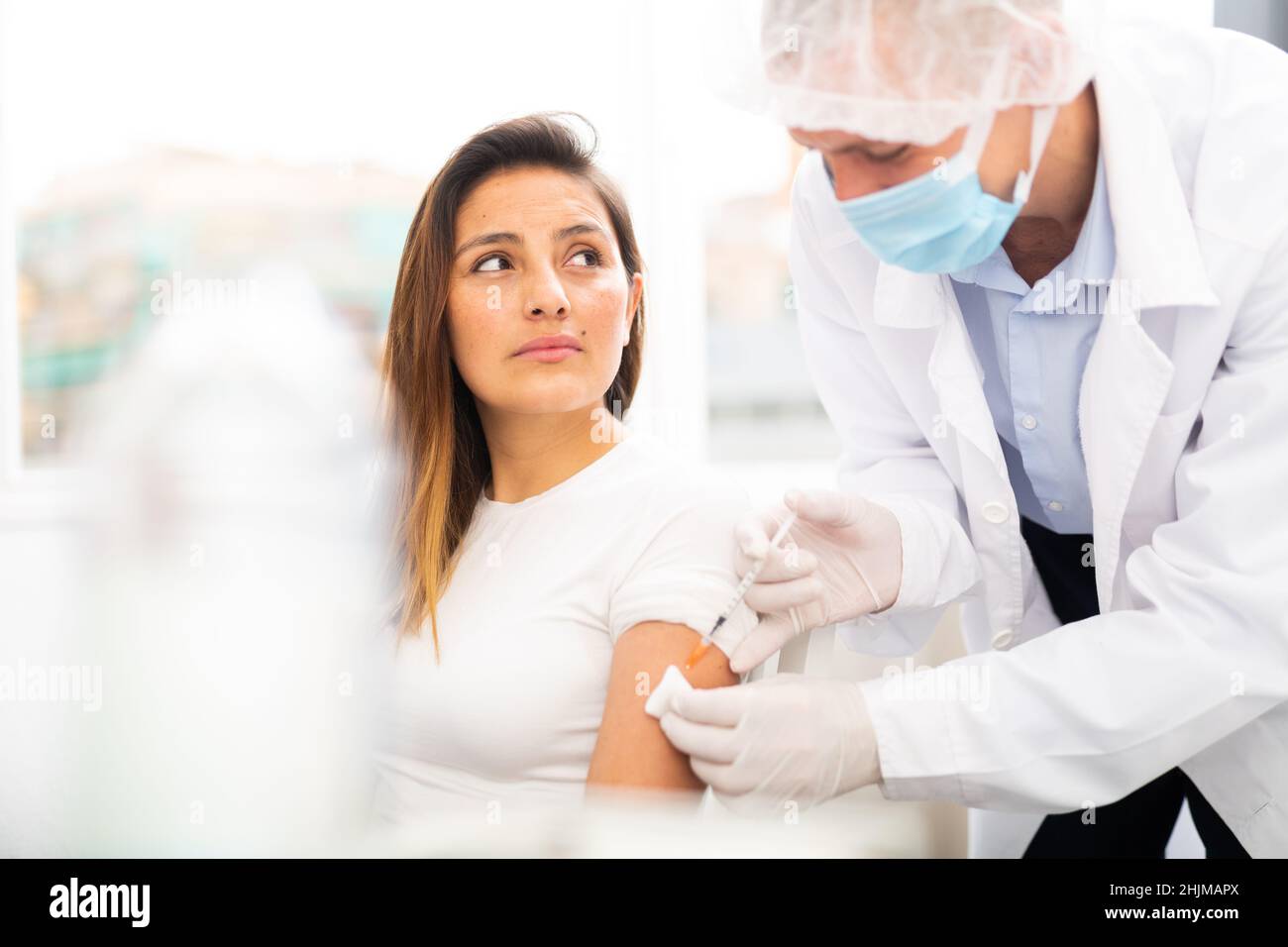 Doctor ready to make injection to adult female visitor Stock Photo - Alamy