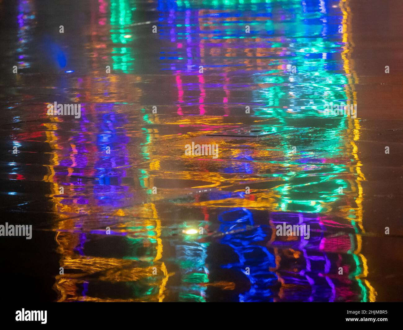 Reflection on the Wet Floor of Colored Lights on a Dark Background Stock Photo