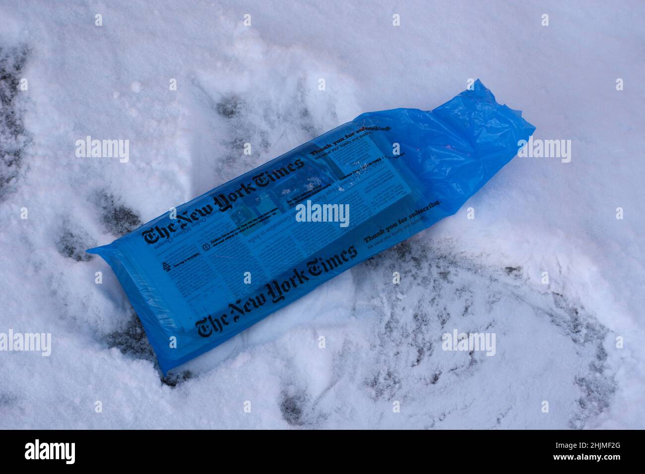 A bagged copy of The New York Times on snow-covered driveway in Santa Fe, New Mexico. Stock Photo