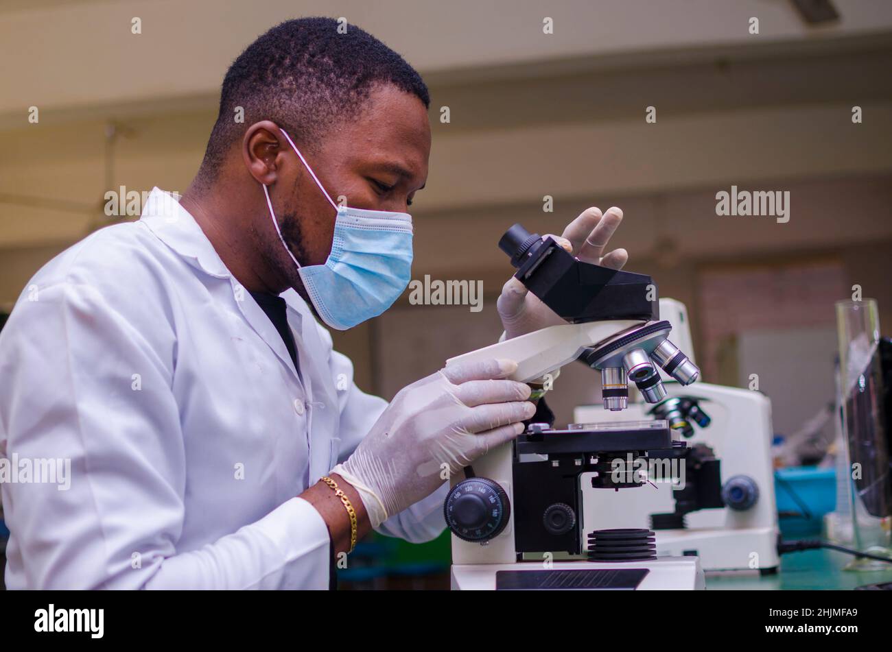 young scientist looking through a microscope in a laboratory. Young scientist doing some research. Stock Photo