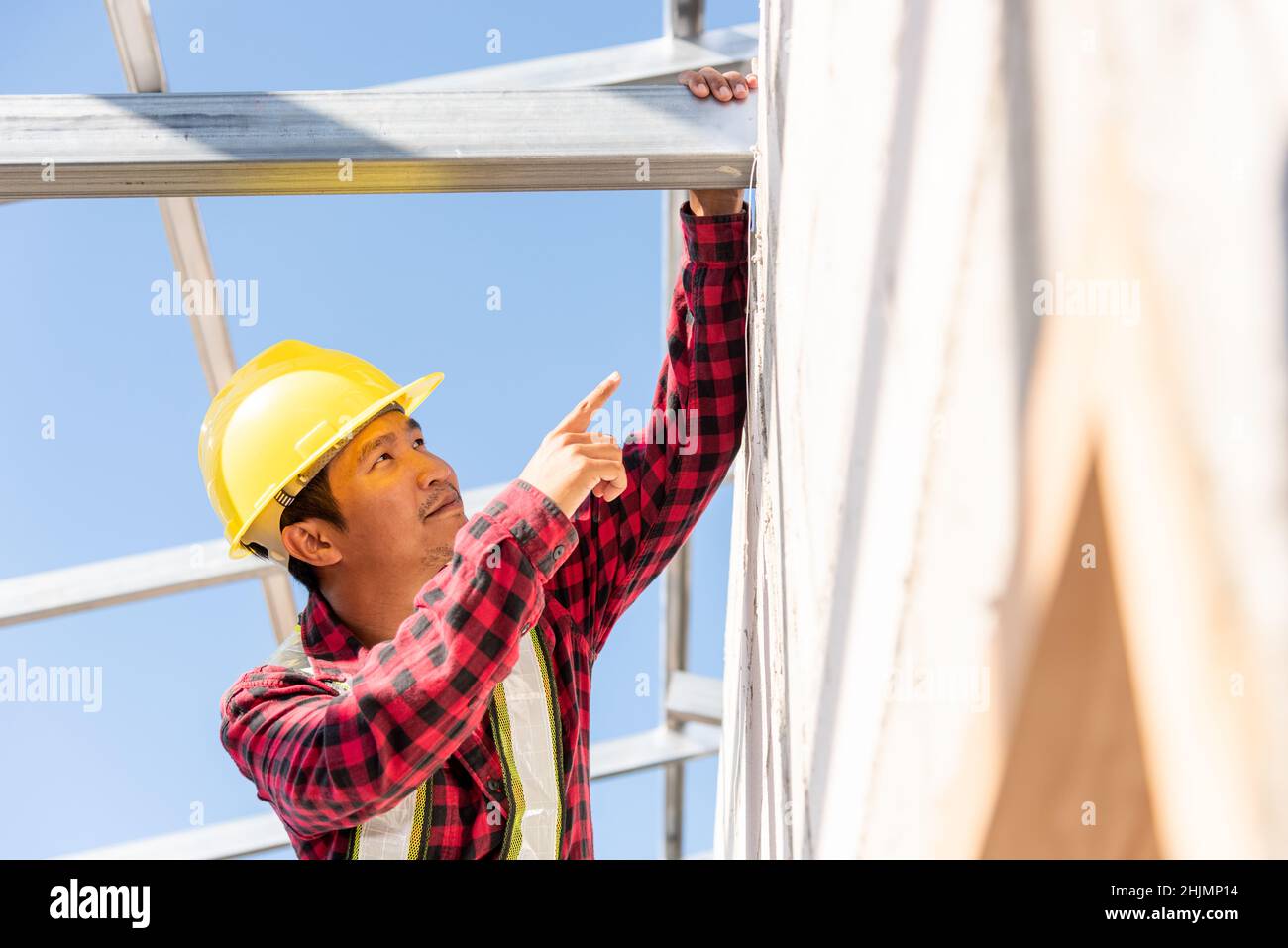 Construction worker or contractor checking house frame, worker roofer builder working on steel roof structure on building  construction site Stock Photo