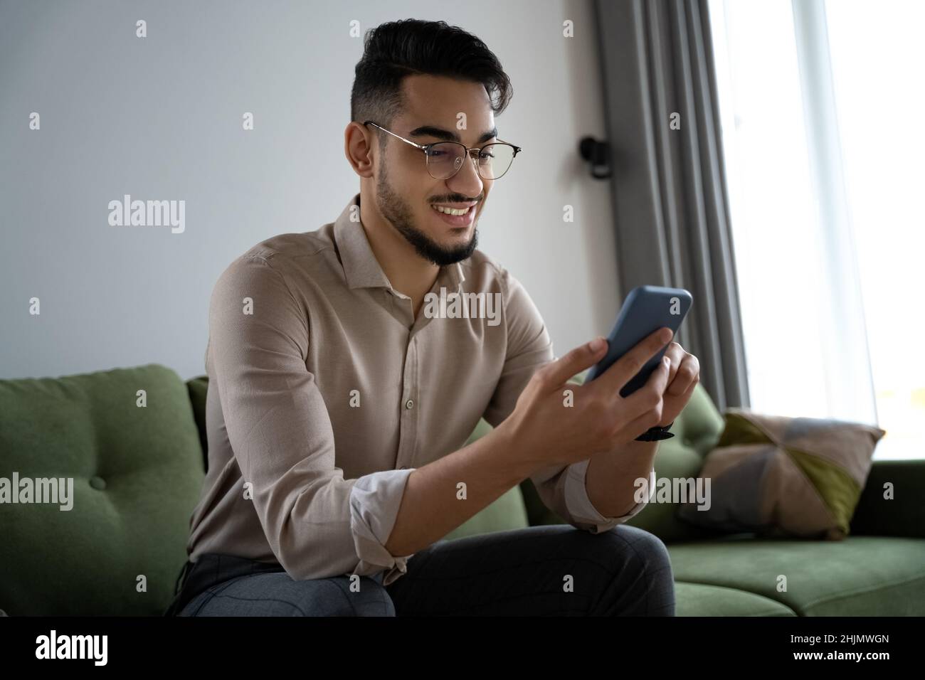 Young man using phone and internet technology sitting on sofa rest at home Stock Photo