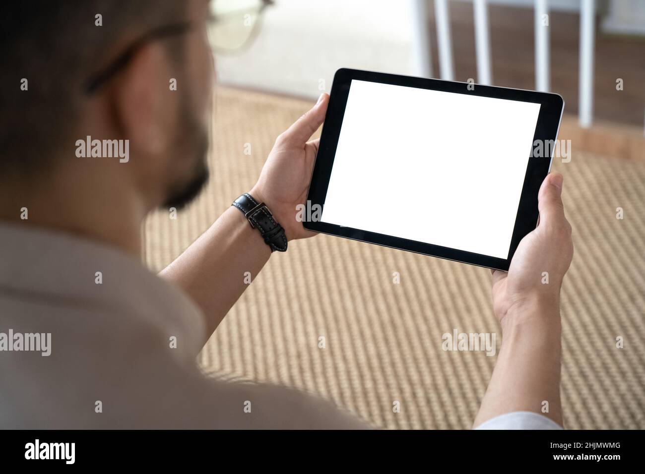 Closeup of Indian man holding digital tablet sitting on sofa at home office Stock Photo