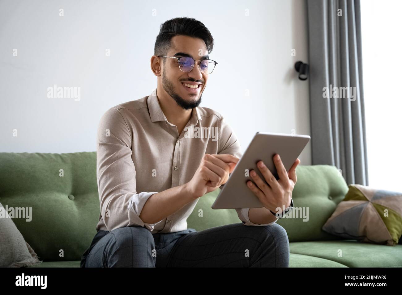 Young man using digital tablet computer sitting on sofa at home office Stock Photo