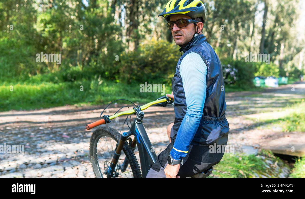 Portrait of mountain biker sitting on his bike wearing helmet, goggles ...