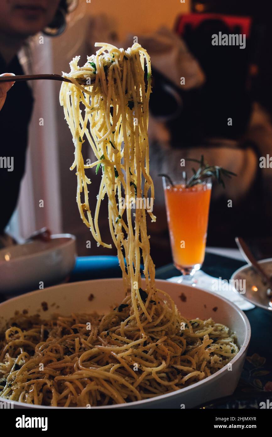 serving spaghetti pasta out of pan at dinner table Stock Photo