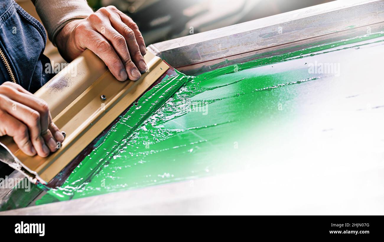 gentage pedicab Kritisk serigraph printing production. silk screen textile printery. male hand with  a squeegee. creating print on t-shirt in workshop Stock Photo - Alamy