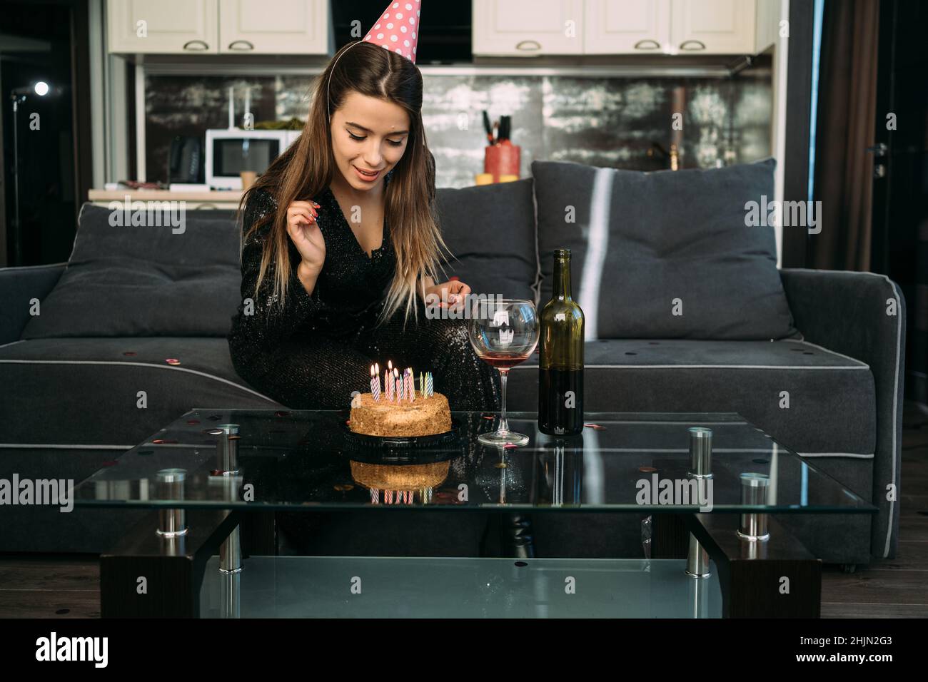 Happy young woman lights candles on cake, birthday party at home, sweet dessert with candles, caucasian girl celebrates 25th birthday Stock Photo