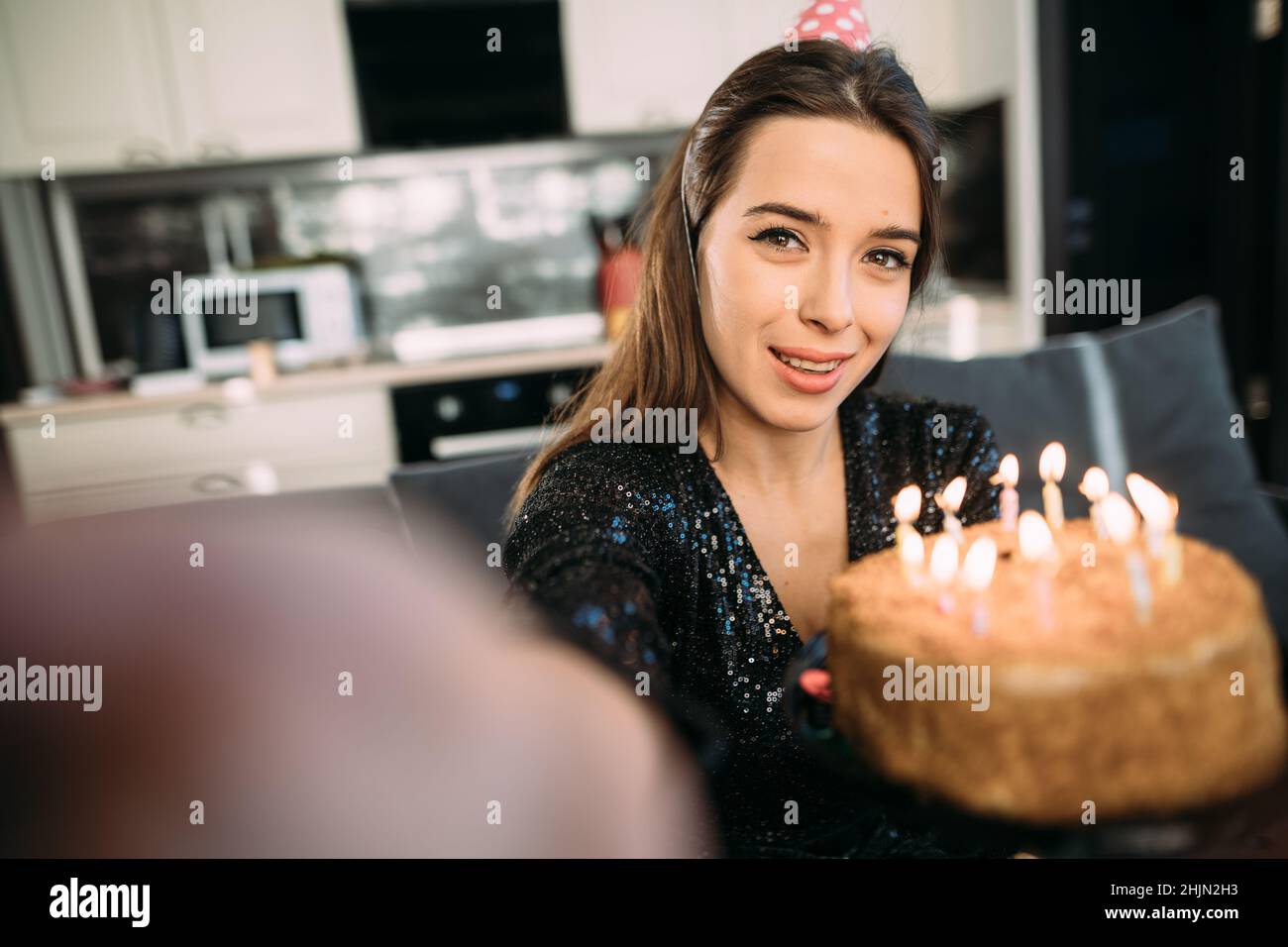 Happy woman blogger filming herself on camera on her birthday, caucasian brunette girl with cake and candles at home, party for one in anniversary Stock Photo