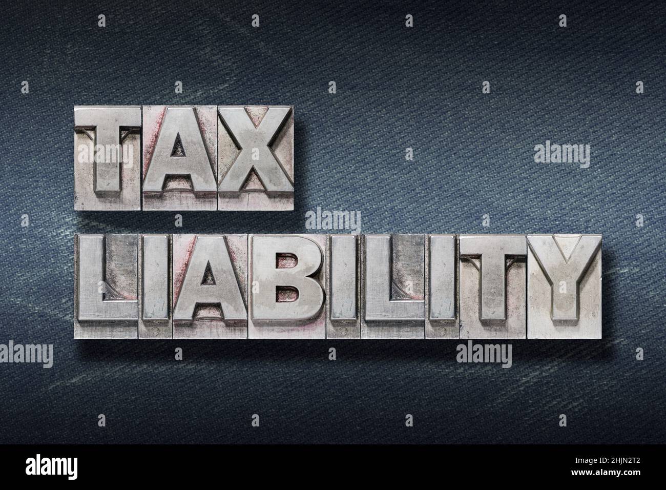 tax liability phrase made from metallic letterpress on dark jeans background Stock Photo