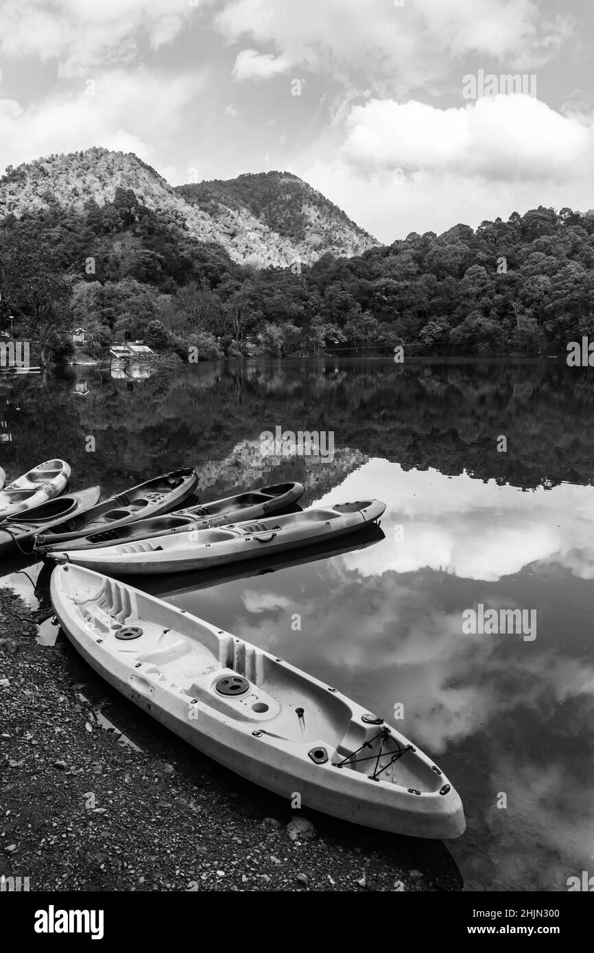 Boats on the shore of a lake with the reflection of sky and hills falling on water Stock Photo
