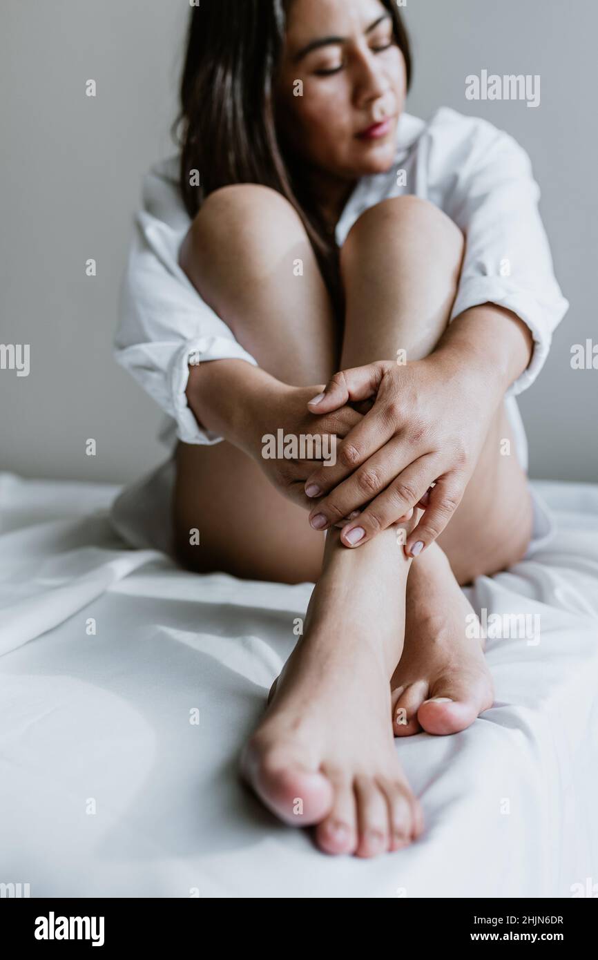 https://c8.alamy.com/comp/2HJN6DR/young-latin-woman-sitting-on-bed-wearing-white-robe-showing-legs-at-home-in-mexico-city-2HJN6DR.jpg
