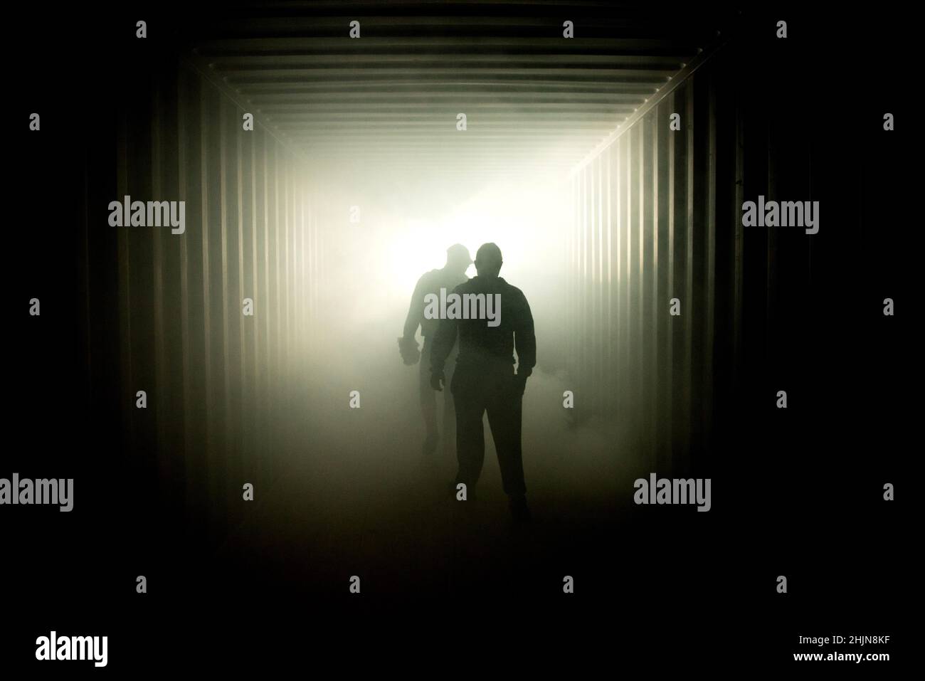 Silhouette of people walking in a dark subway tunnel to the light Stock Photo