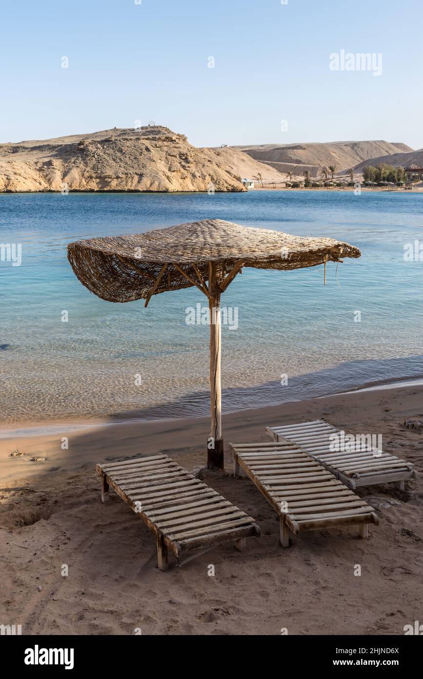 Hurghada, Egypt - June 03, 2021: View of the empty beach with no people during a pandemic. Wooden umbrella and sun loungers. Small beautiful Secret ba Stock Photo