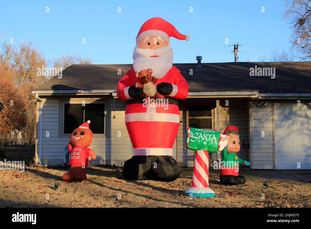 A Santa with a mailbox and helper Elves with blue sky during the Holiday season in Kansas Stock Photo