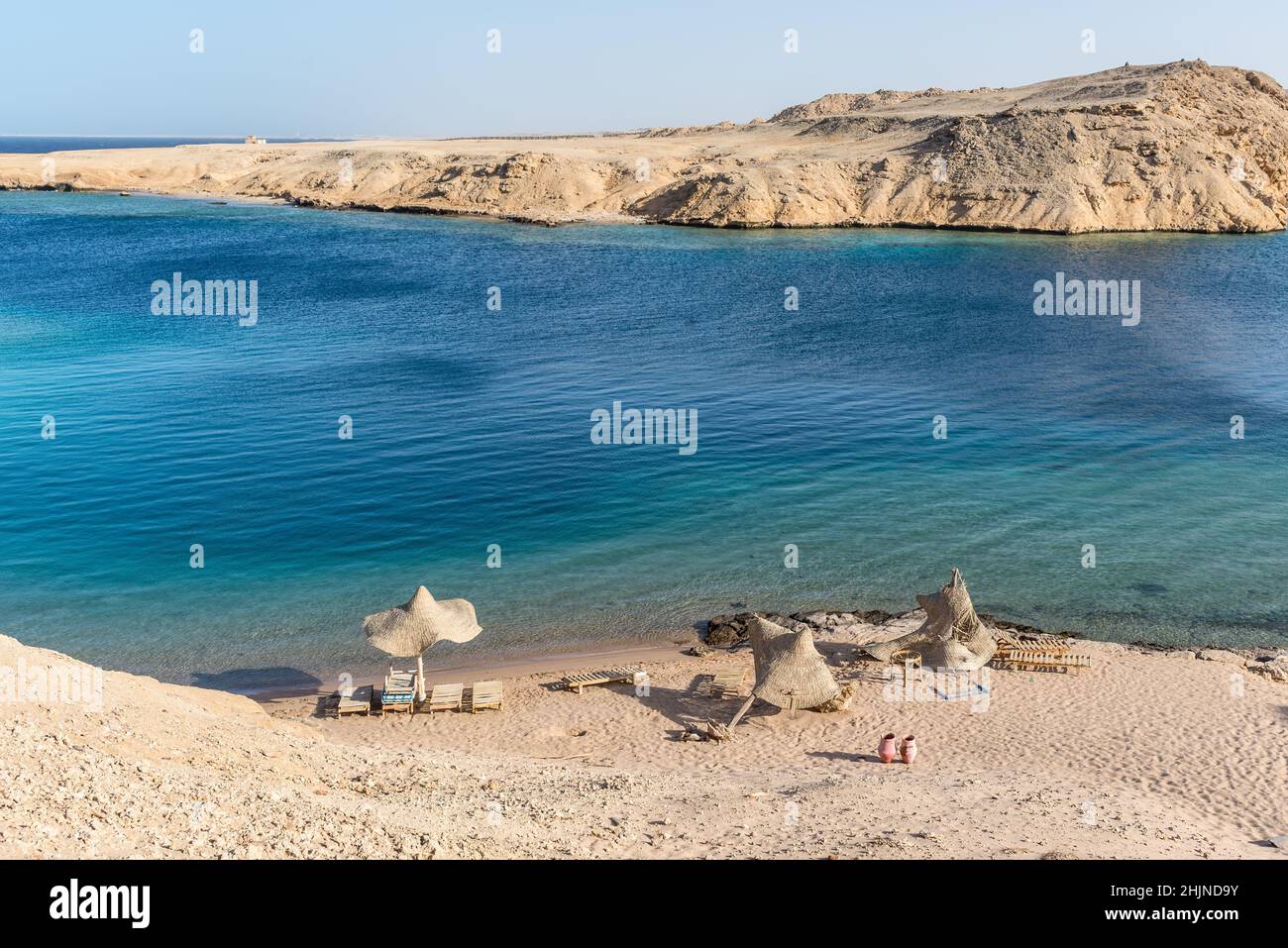Empty beach with no people during a pandemic. Abandoned wooden umbrella. Beautiful quiet Secret bay. Stock Photo