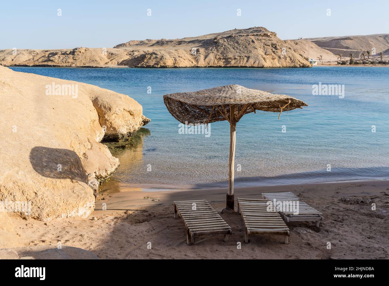 Empty beach with no people during a pandemic. Wooden umbrella and sun loungers. Small beautiful Secret bay. Stock Photo