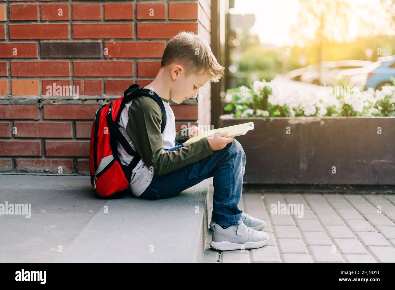 Back to school. Cute child with backpack, holding notepad and training books. School boy pupil with bag. Elementary school student going to classes Stock Photo