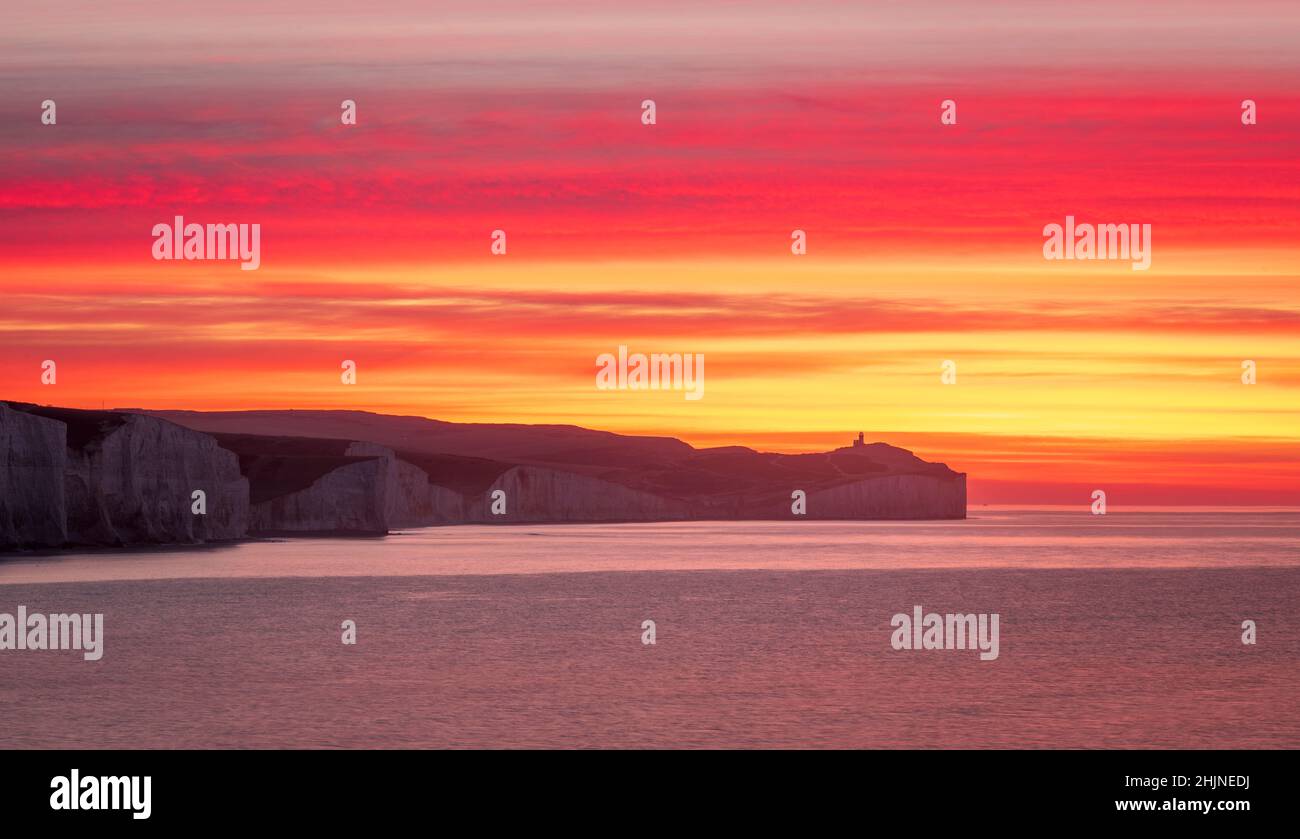 Colourful January sunrise from the cliff edge of Seaford Head looking out towards the Seven Sisters and Belle Tout lighthouse on the east Sussex coast Stock Photo