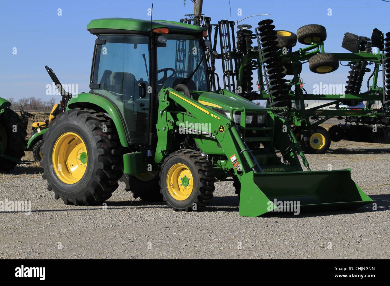 A John Deere farm tractor  in a Dealership with blue sky in the background in Kansas Stock Photo