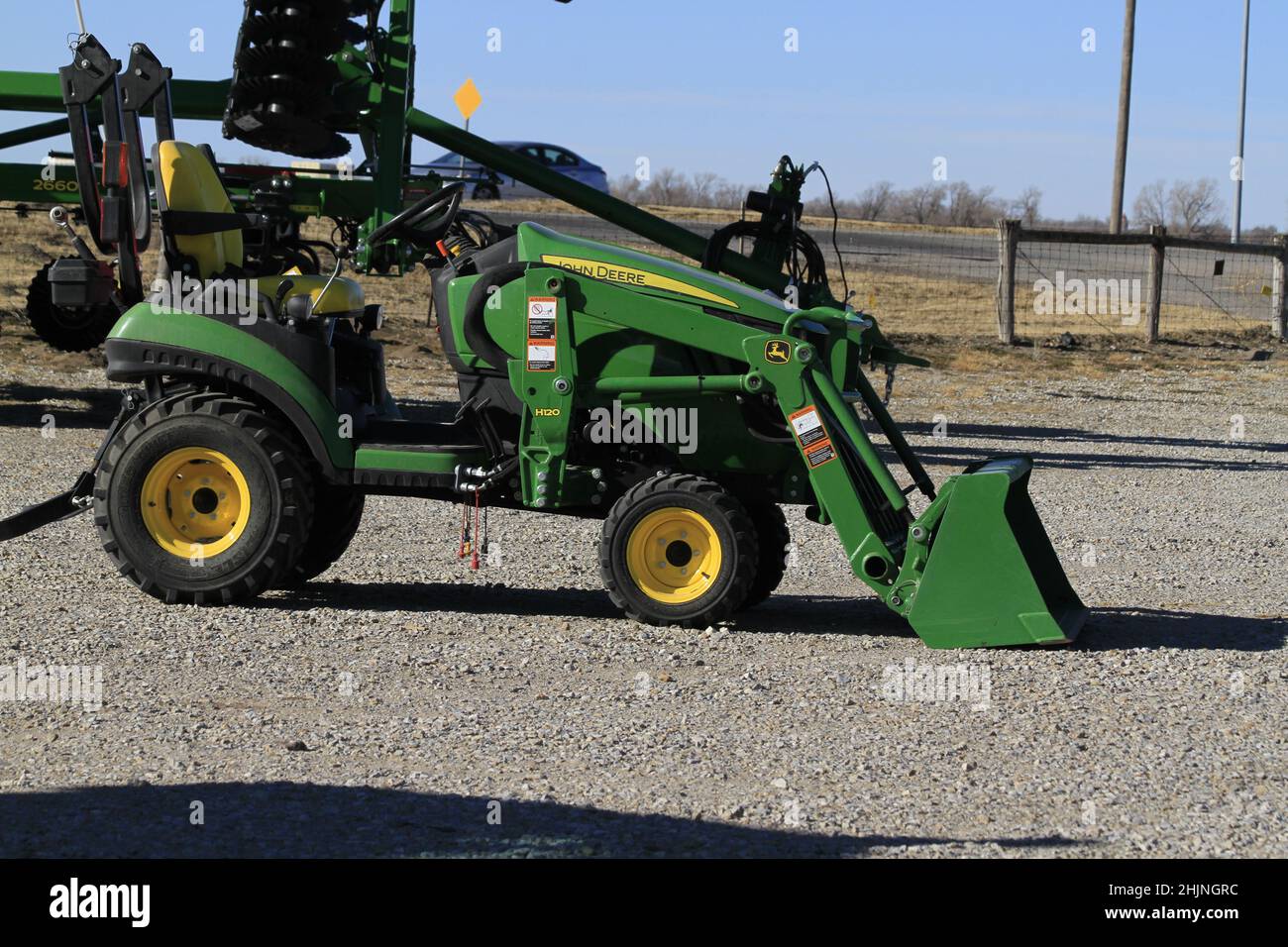 A John Deere farm tractor in a Dealership with blue sky in the