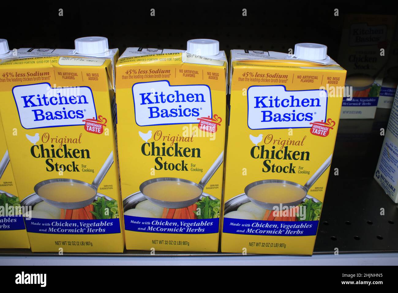 A closeup of Kitchen Basics Chicken Stock that's bright and colorful in a box on a metal shelf in a Dillons grocery store in Kansas Stock Photo