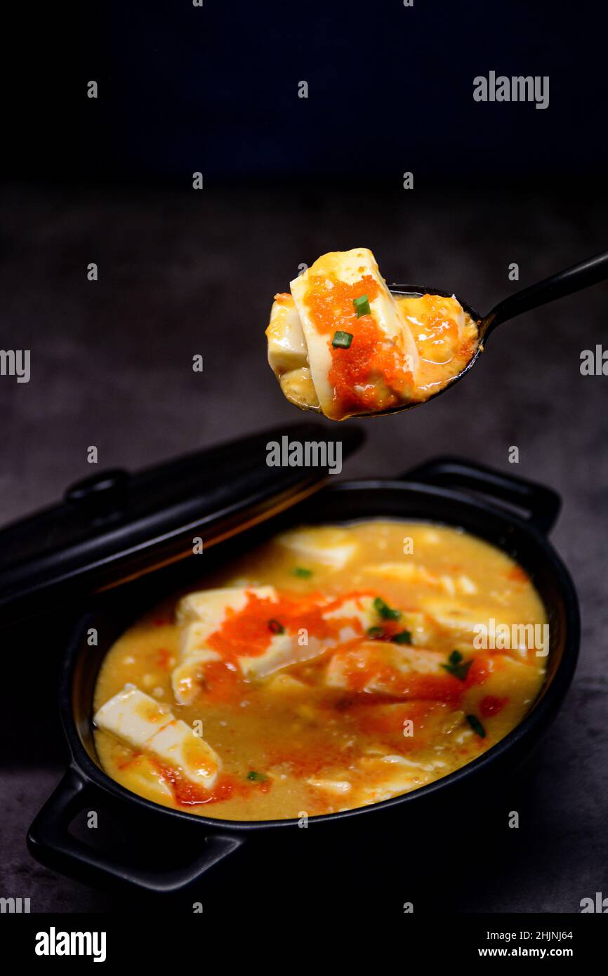Vertical shot of salted egg yolk with fried tofu in a clay pot Stock