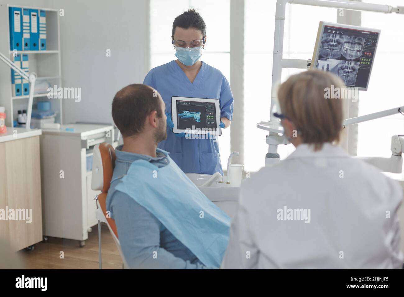 Dentist assistant wearing face mask showing teeth radiography using