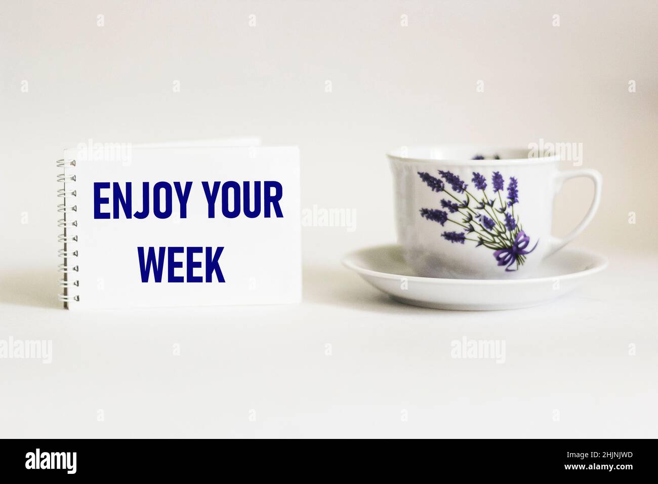 Notepad with words Enjoy the week on white background with vintage cup ...