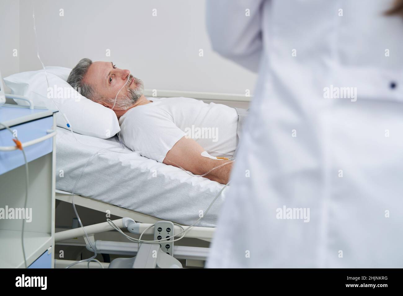 Recumbent patient staring at attending doctor during ward round Stock