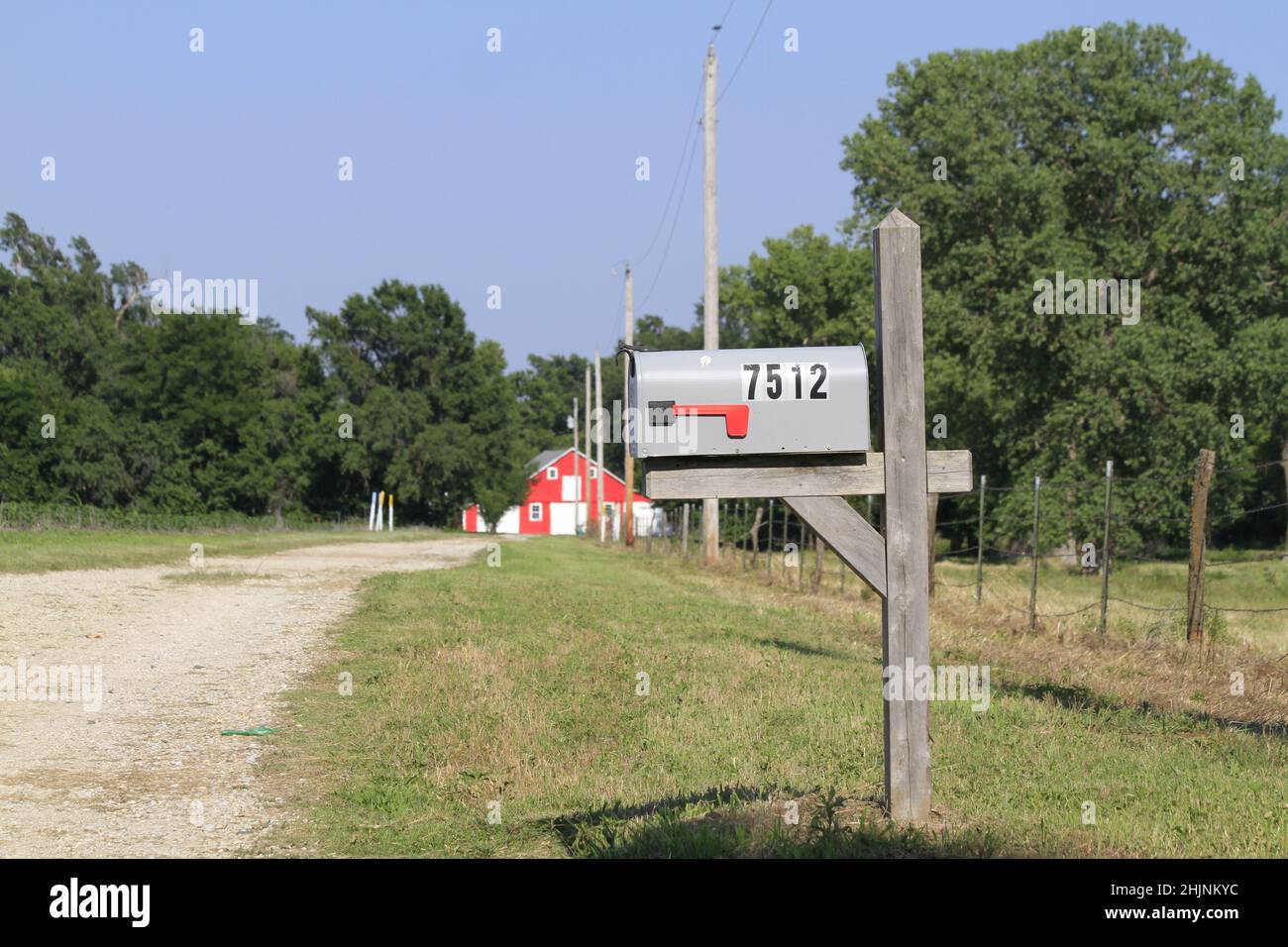A Kansas country mailbox with green grass, trees, and blue sky out in the country Stock Photo