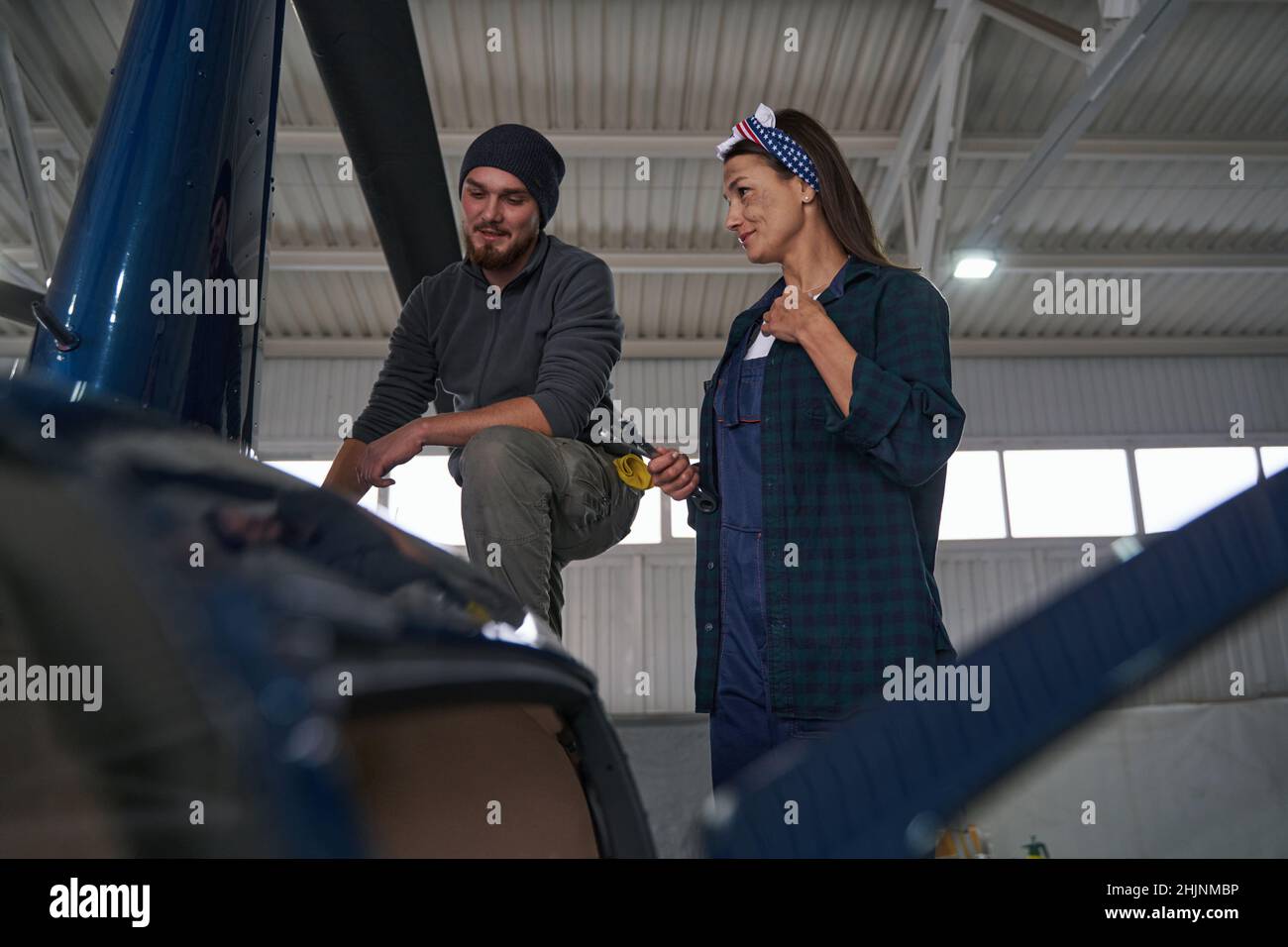 Two engineers using special tools while analyzing details of copter in hangar Stock Photo